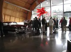 A group of people standing around in front of an antique car.