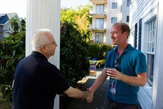 Two men shaking hands outside a building.