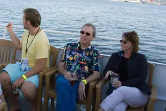 Three people sitting on a boat in the water.