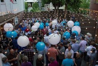 A crowd of people holding balloons and lit candles.