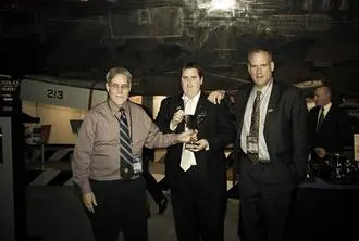 Three men in suits and ties holding a trophy.