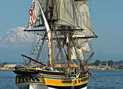 A large sail boat in the water near other boats.